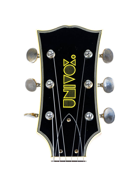 Close-up of the headstock of a Univox Gimmie U-1988 guitar, displaying the name "Zon," made in Japan, 1974-75.