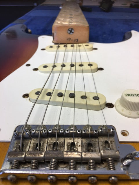 Close-up of the neck of a vintage 1958 Fender Stratocaster, focusing on the frets and unique wood texture.