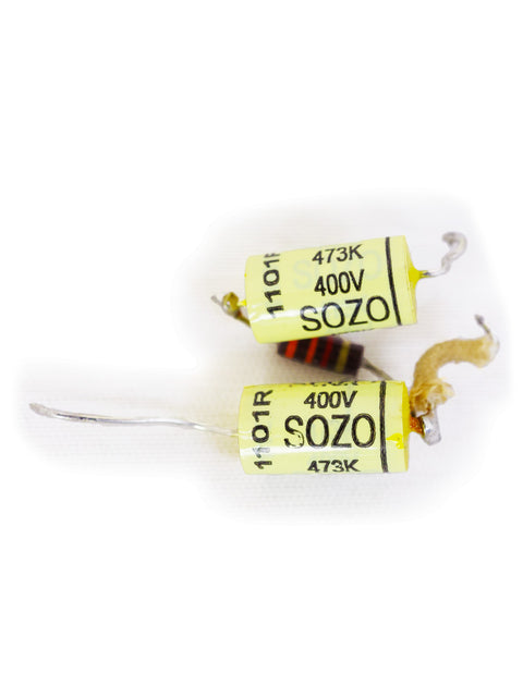 Close-up of two yellow and black capacitors placed on a clean white background, highlighting their unique appearance.
