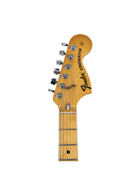 Close-up shot of a 1976 Fender Stratocaster headstock, emphasizing its vintage style and intricate tuning pegs.
