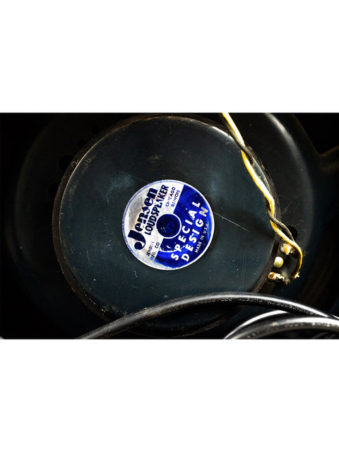 Close-up shot of a record player with a blue label, complemented by a vintage Fender Vibroverb Amp from 1964.