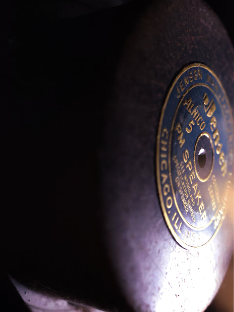 Detailed close-up of a record player under bright light, featuring a classic Fender Bassman Amplifier from 1952/53 in the background.
