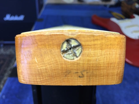 Detailed view of a 1957 Fender Stratocaster guitar, showcasing its wooden headstock and striking Dakota Red color.