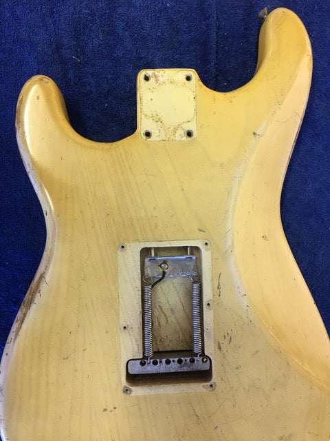 Detailed view of a 1959 Fender Stratocaster guitar, showcasing its metal plate, blond body, and maple neck.