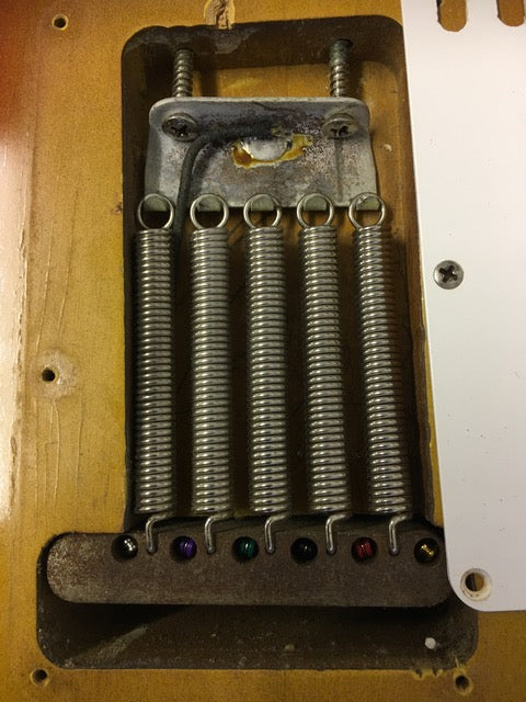 Detailed view of a 1964 Fender L Series Stratocaster, featuring springs and screws against a Fiesta Red finish.