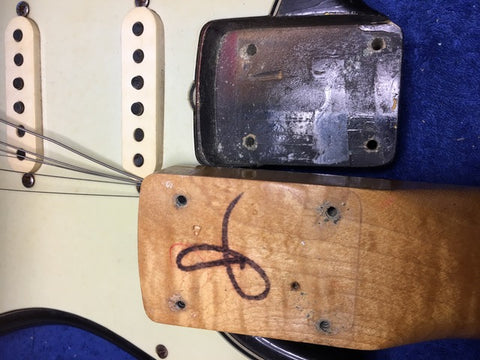 Detailed view of a 1964 Fender L Series Stratocaster in Fiesta Red, showcasing a sticker on its surface.