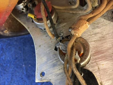 Detailed view of a 1964 Fiesta Red Fender L Series Stratocaster, highlighting the guitar's wires and craftsmanship.