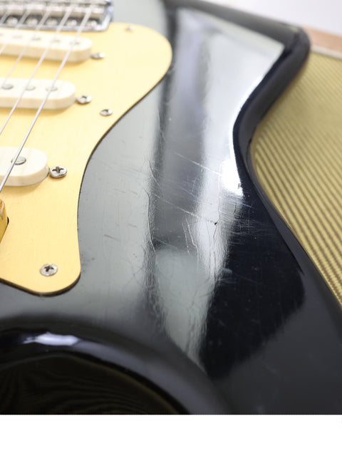 Detailed view of a black Fender AVRI ‘56 Stratocaster guitar, highlighting its elegant finish and iconic shape.