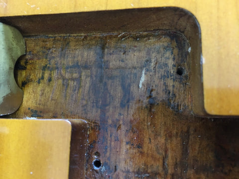 Detailed view of a wooden table showcasing a metal component from a vintage 1958/59 Fender Precision Bass Refin.