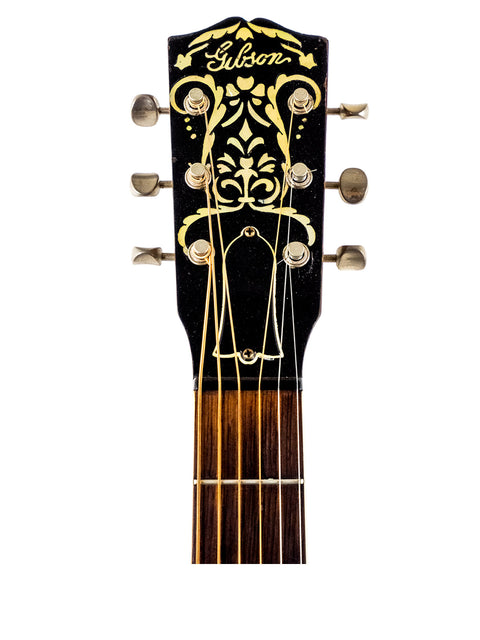 Detailed view of the headstock on a vintage Gibson L 7 Special acoustic guitar, highlighting its gold and black aesthetics.