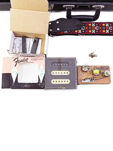 Display of a 1968 Fender Stratocaster guitar with its case, strings, pick, strap, and pick, highlighting vintage charm.