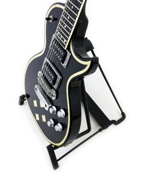 Eye-catching black electric guitar, Greco Zemaitis GZ-2600IF (Japan 2004), showcased on a stand with a minimalist white background.