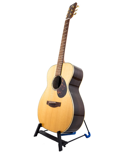 Gerard Gilet 000 14 Fret Acoustic guitar on a stand against a clean white background, showcasing its elegant design.