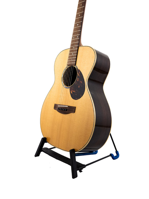 Gerard Gilet 000 14 Fret Acoustic guitar rests on a stand, set against a clean white background.