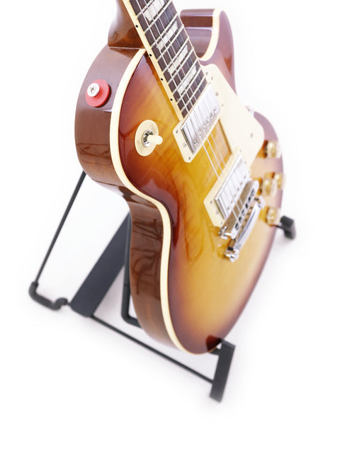 Gibson Les Paul Traditional guitar displayed on a stand, set against a pristine white backdrop, highlighting its craftsmanship.