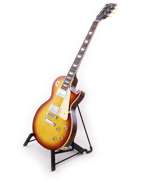Gibson Les Paul Traditional guitar on a stand against a clean white background, showcasing its elegant design and craftsmanship.
