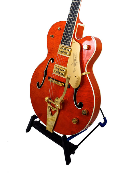 Gretsch Chet Atkins G6120 guitar with a gold neck, displayed on a sleek black stand.