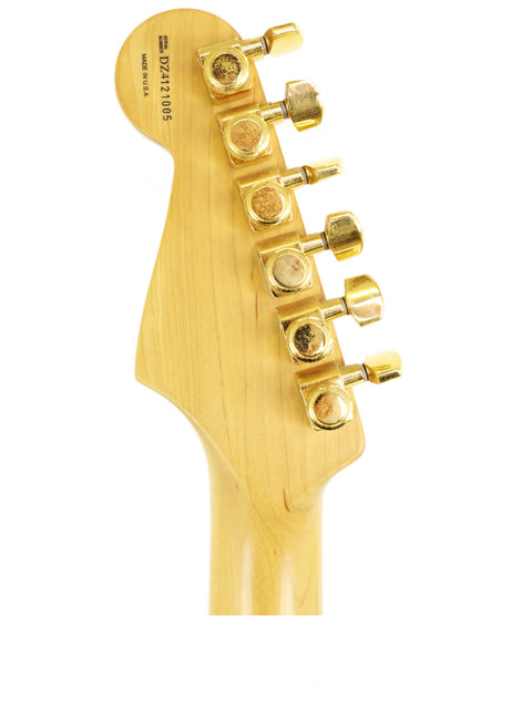 Headstock of a guitar with gold tuning pegs on a white background.