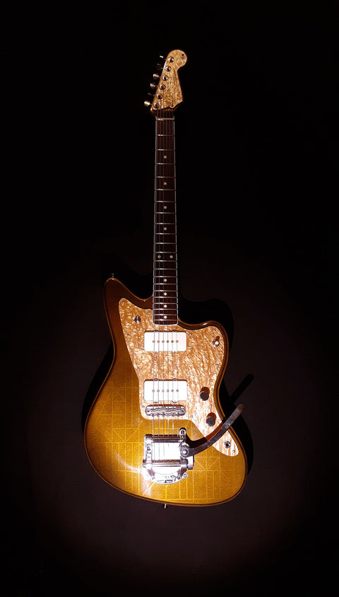 In a dim setting, a Zachary & Mercer Mastermind “Deluxe” Offset guitar shines under a gentle light.