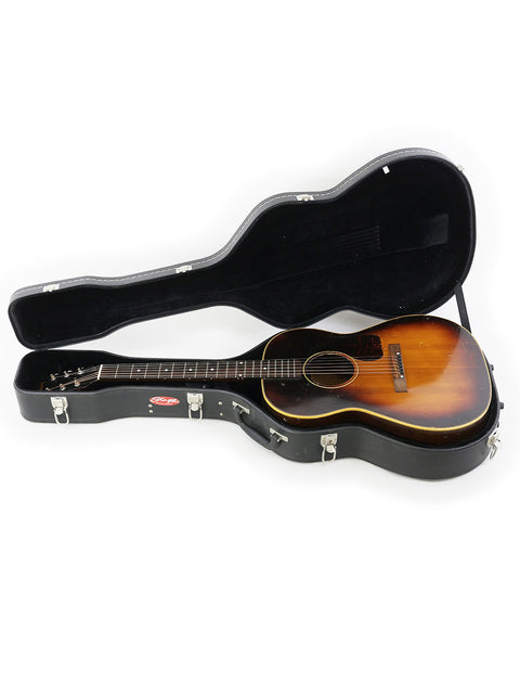 Inside a guitar case, a 1954 vintage Gibson LG-2 rests, representing iconic American music history.