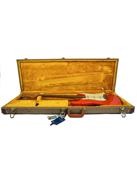 Inside a guitar case, a striking Fiesta Red Fender American Vintage 62 Strat from 1996 is prominently displayed.