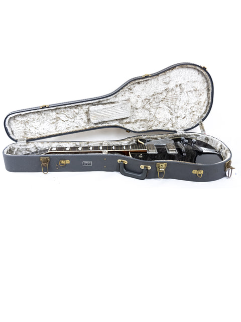 Inside a guitar case lies a black Gretsch Duo Jet 6128, a vintage model from Japan, highlighting its elegant shape.