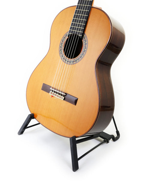 Isolated on a white background, a Ramirez 4NE guitar from Spain (2012) rests on a stand, highlighting its craftsmanship.