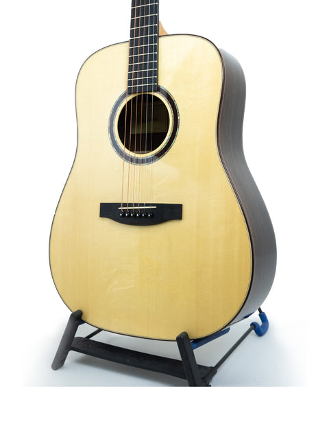 Lakewood D-32 Dreadnought guitar resting on a stand, with a stark white background that accentuates its fine details.