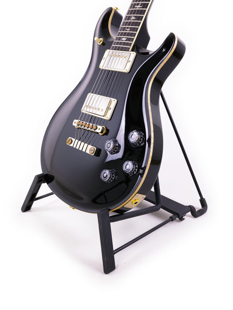 PRS McCarty 594 guitar in black, elegantly displayed on a stand with a bright white background.