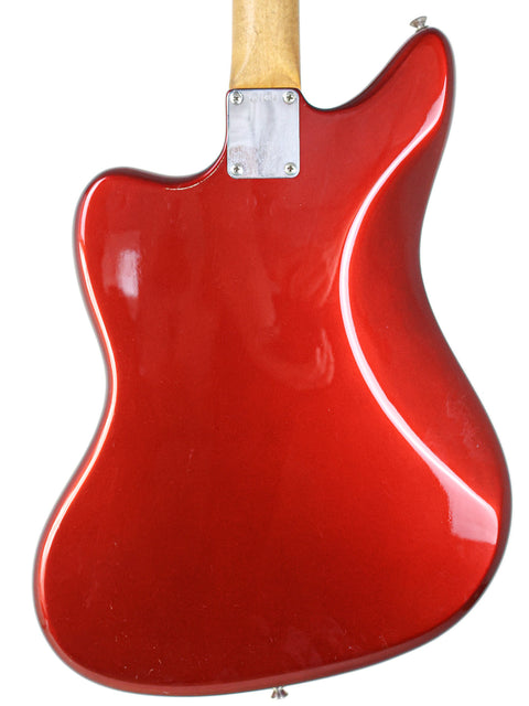 Red vintage 1964 Fender Jaguar guitar with a wooden body and neck, showcasing its classic design and craftsmanship.