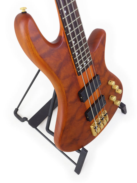 Schecter Stiletto Studio 4 bass guitar elegantly positioned on a stand, with a minimalist white background enhancing its features.