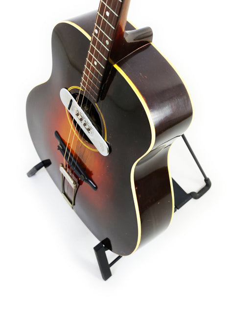 Stunning 1934 Gibson TG50 Tenor Guitar on a stand, ideal for musicians and collectors, with a minimalist white background.