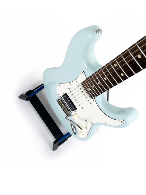 Suhr Classic Pro electric guitar in blue, displayed on a stand with a white backdrop.