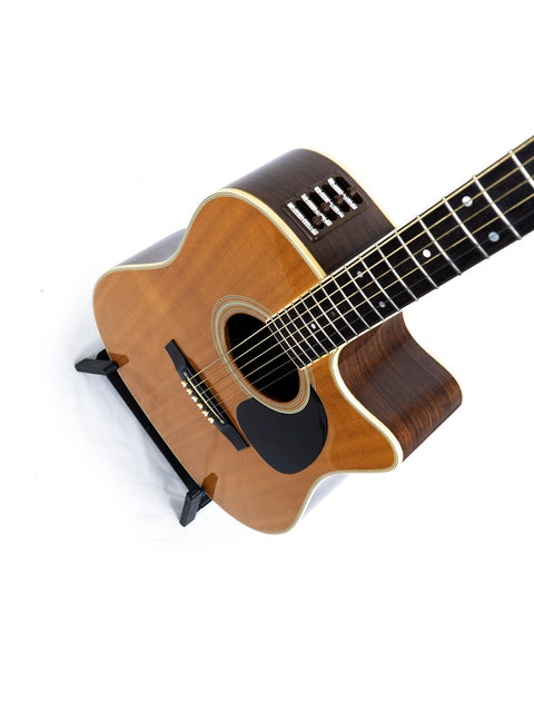 Takamine EF 360SC acoustic guitar from 1988 displayed on a stand with a white backdrop.