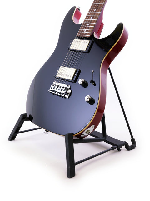 The Suhr Pete Thorn Signature guitar, black and sleek, is positioned on a stand.