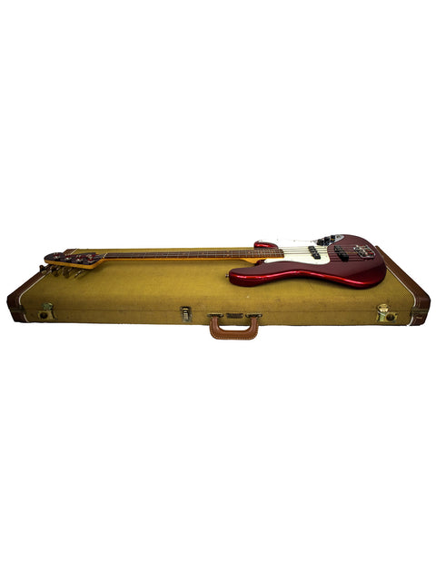 The image displays a guitar case for a Fender Custom Shop ‘62 Jazz Bass Reissue, highlighting its red neck and wooden body.