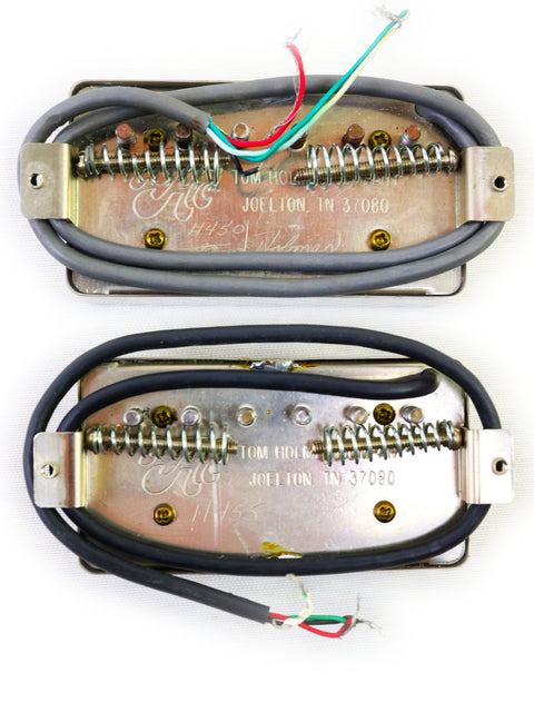 Two Tom Holmes H450/H455 humbucker pickups with wires attached, showcasing their detailed design and craftsmanship.