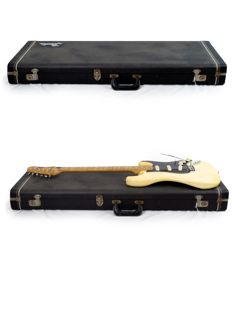Two guitars, featuring a 1976 Fender Stratocaster, arranged in a case with a white backdrop.
