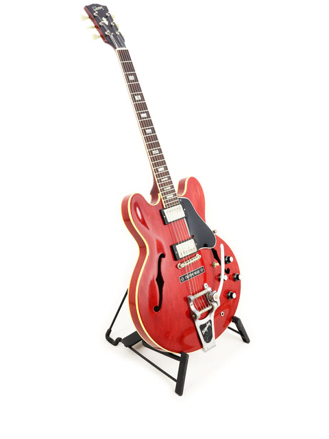 Vintage 1963 red Gibson ES-335 guitar on a stand, highlighting its iconic design.