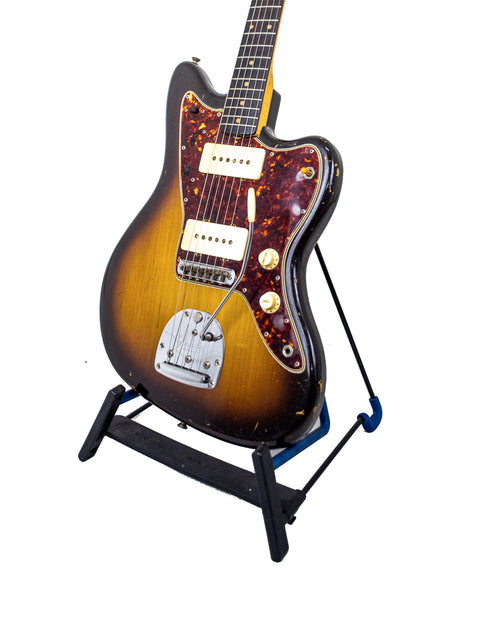 Vintage Fender Jazzmaster guitar on a stand with a sleek black base, showcasing its classic design and craftsmanship.