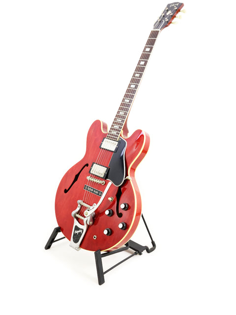 Vintage red Gibson ES-335 guitar from 1963 on a stand, featuring a white background.
