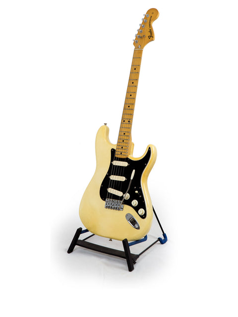 White 1976 Fender Stratocaster guitar on a stand, showcasing a classic black pick guard.