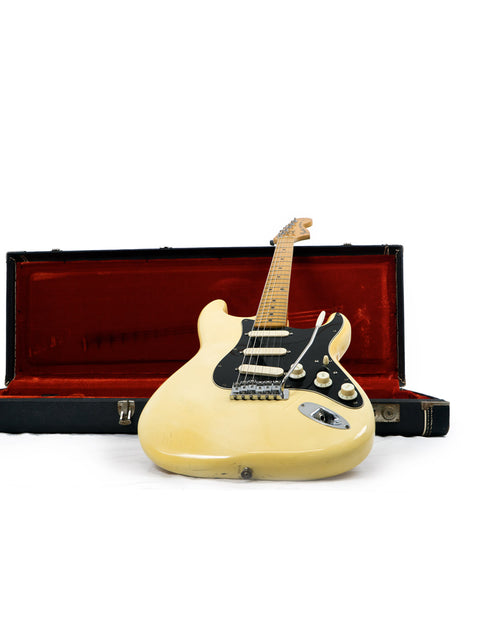 White vintage Fender Stratocaster guitar from 1976 in a red case on a white table.