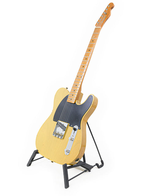 Yellow Fender Master Built Jason Smith Esquire guitar displayed on a stand, showcasing its elegant black body, USA 2018.