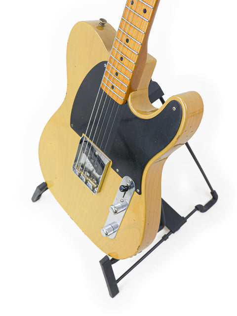 Yellow electric guitar on a stand, featuring the Fender Master Built Jason Smith Esquire model from the USA, 2018.