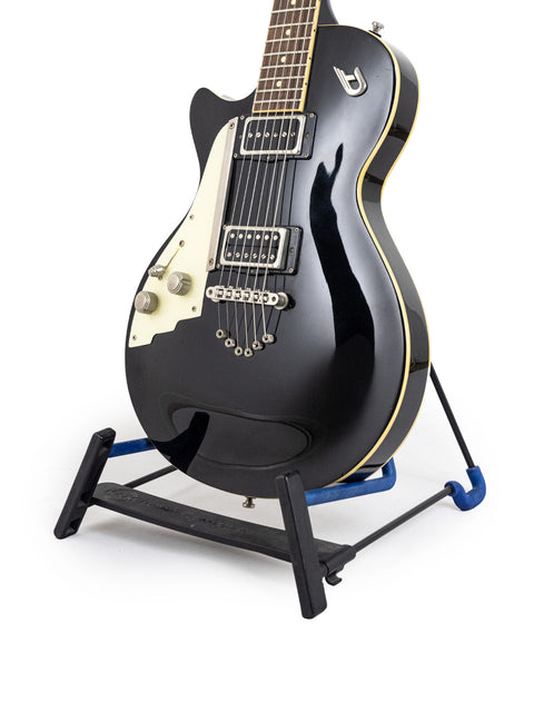 black Duesenberg 49er guitar on a stand with blue legs, showcasing its sleek design and vibrant support.