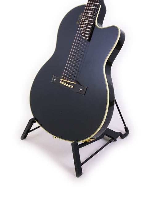 black Gibson Chet Atkins SST guitar on a stand, set against a clean white background, showcasing its sleek design.