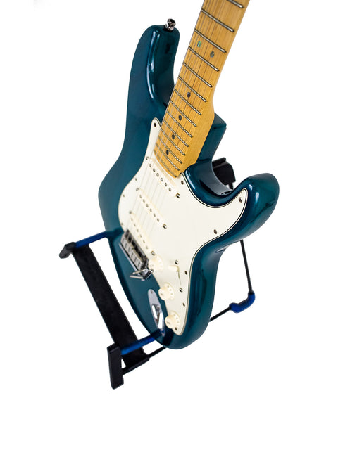 blue Fender American Deluxe Stratocaster electric guitar on a stand, complete with a strap, showcasing its sleek design.