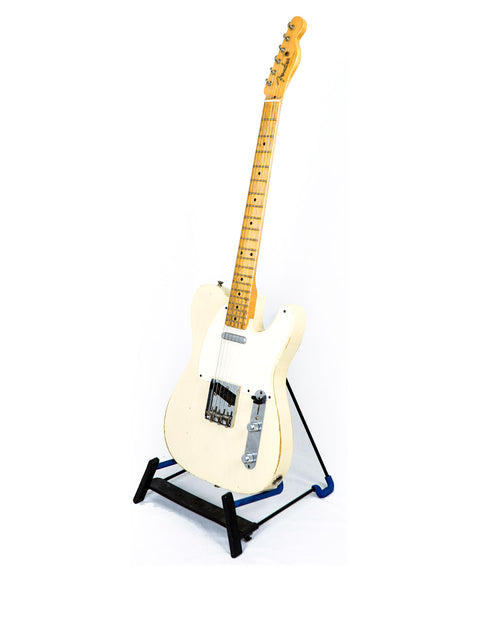 white Fender Custom Shop guitar on a stand with a blue base, showcasing its elegant design and craftsmanship from 2006.