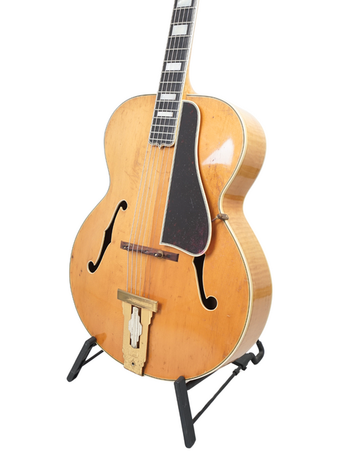 1939 Gibson L-5 guitar resting on a stand, highlighted by a bright white background.